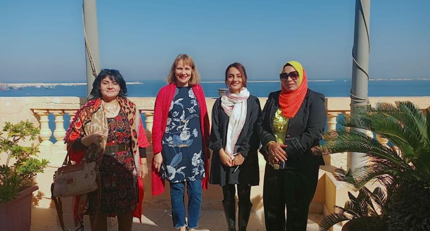 Four women standing in a row, they are smiling